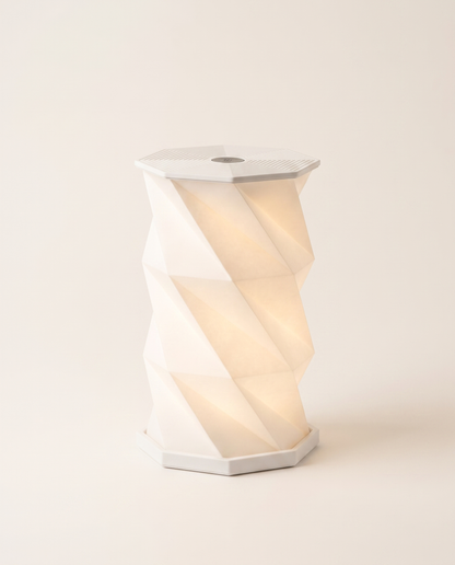 Lumina Fold origami paper table lamp lit on a neutral background
